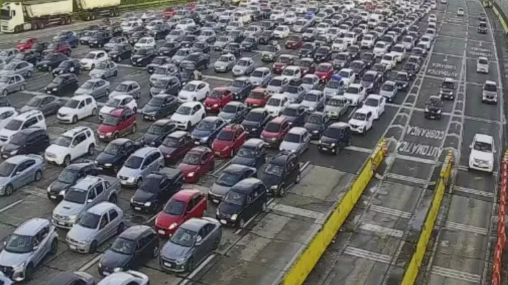 Vista aérea de uma praça de pedágio em São Paulo, com várias pistas e muitos carros parados em congestionamento.