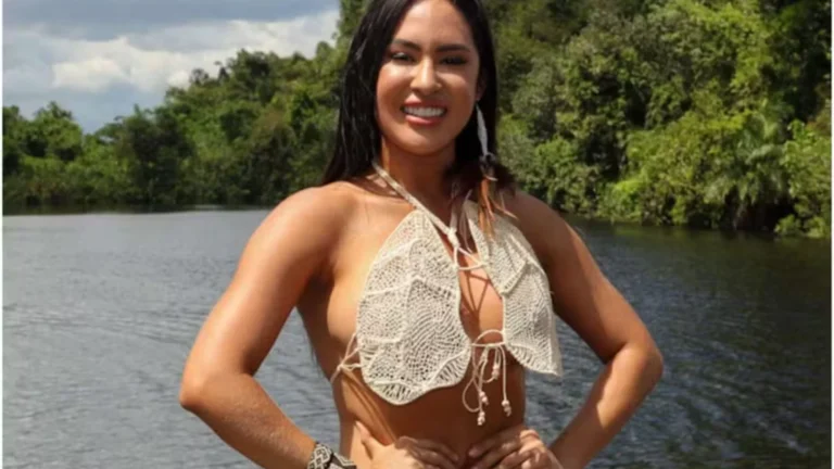 Isabelle Nogueira sorrindo, usando um cropped de crochê, com um rio e mata verde ao fundo, representando a beleza do Nordeste